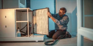 A person cleaning a dirty filter from a central air conditioner.