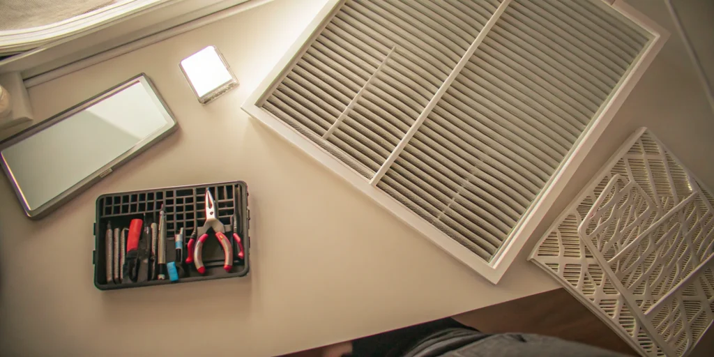 An HVAC air filter, vent cover, and tools for a yearly maintenance service to determine cost.